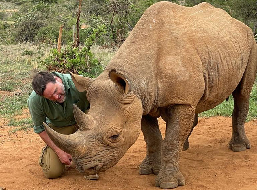 Henry Cookson kneeling next to a rhino