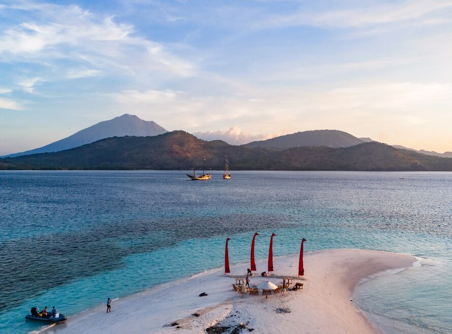 Beach setup with two phinisi yachts in the background